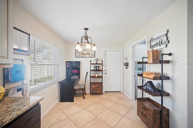 dining area with light tile patterned floors, baseboards, a chandelier, and washer / dryer