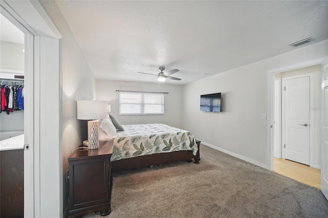 carpeted bedroom featuring baseboards, visible vents, ceiling fan, and a textured ceiling