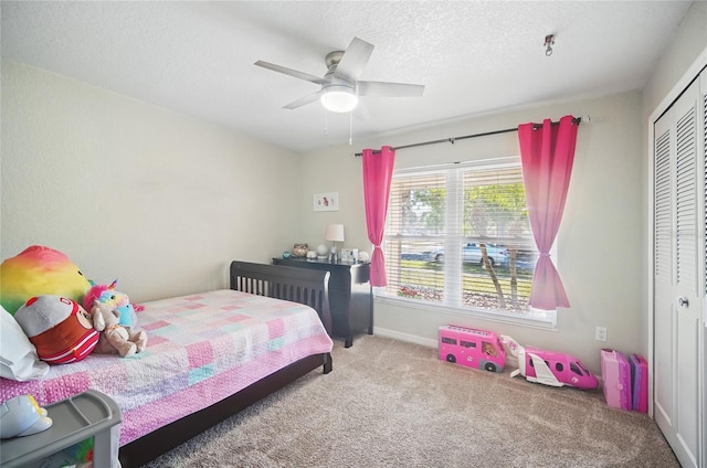 bedroom with a textured ceiling, ceiling fan, a closet, and carpet