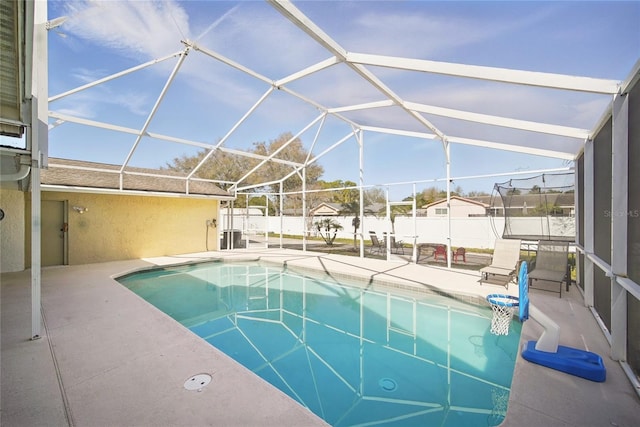 view of swimming pool featuring glass enclosure, a patio area, a fenced backyard, and a fenced in pool