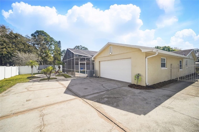 view of front facade with a lanai, fence private yard, a garage, concrete driveway, and stucco siding