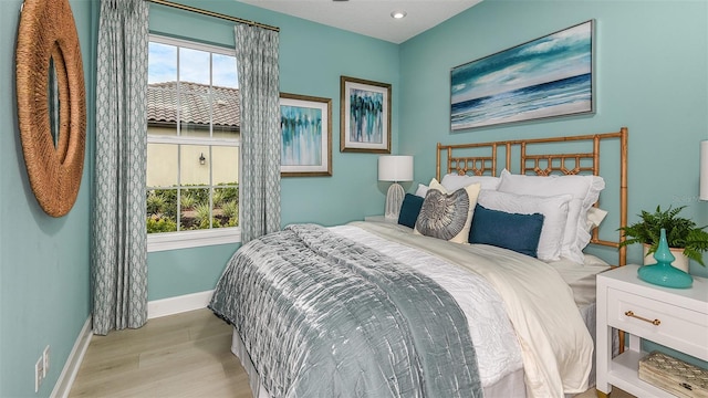 bedroom with multiple windows, baseboards, and wood finished floors