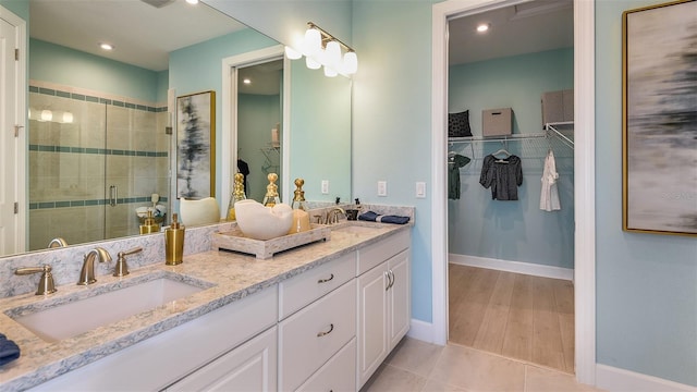 bathroom with a stall shower, tile patterned flooring, a sink, and double vanity