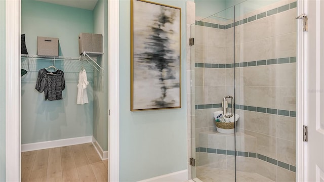 full bathroom with a stall shower, wood finished floors, and baseboards