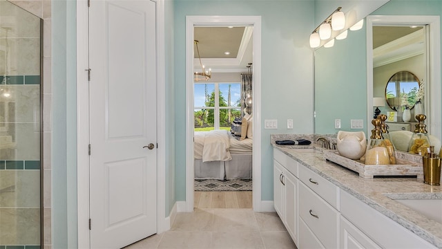 ensuite bathroom featuring ensuite bathroom, a sink, ornamental molding, tile patterned floors, and a raised ceiling