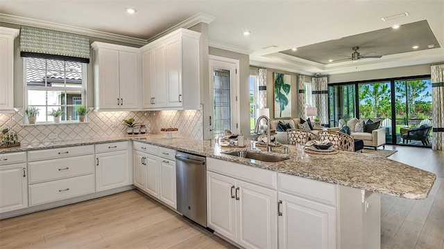 kitchen with a peninsula, a sink, open floor plan, stainless steel dishwasher, and crown molding