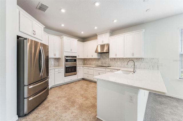 kitchen featuring visible vents, appliances with stainless steel finishes, a peninsula, under cabinet range hood, and a sink