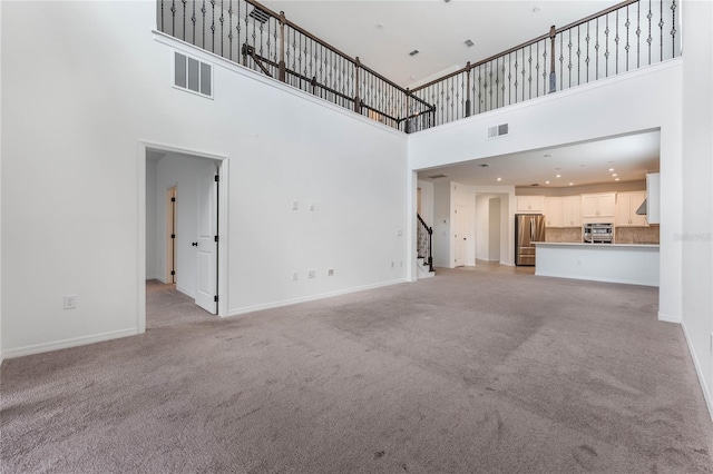 unfurnished living room with light carpet, stairway, baseboards, and visible vents