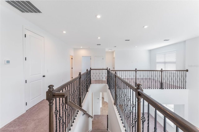 hall featuring carpet floors, recessed lighting, visible vents, and an upstairs landing