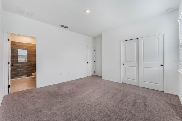 unfurnished bedroom featuring baseboards, ensuite bath, visible vents, and carpet flooring