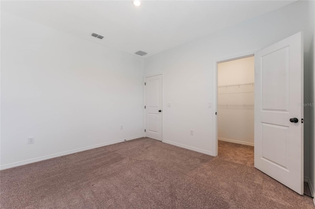 unfurnished bedroom with visible vents, light carpet, baseboards, and a spacious closet