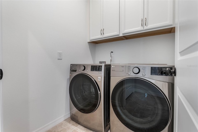 laundry room with light tile patterned floors, separate washer and dryer, cabinet space, and baseboards