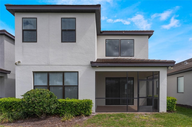 back of property featuring a sunroom and stucco siding