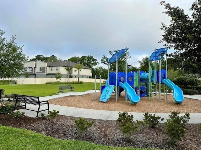 community play area featuring a lawn and fence