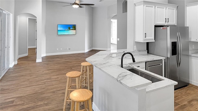 kitchen with a sink, wood finished floors, open floor plan, arched walkways, and stainless steel fridge with ice dispenser