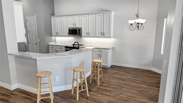 kitchen featuring stainless steel appliances, a breakfast bar, dark wood finished floors, and white cabinetry