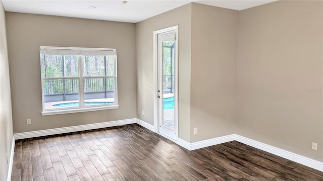 spare room featuring dark wood finished floors and baseboards