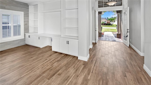 interior space with light wood-type flooring, baseboards, and built in desk