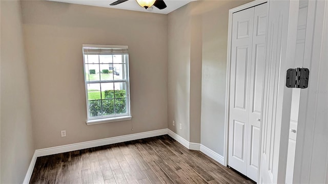 unfurnished bedroom featuring a closet, baseboards, dark wood finished floors, and a ceiling fan