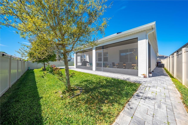 rear view of property with a sunroom, a fenced backyard, a lawn, and stucco siding