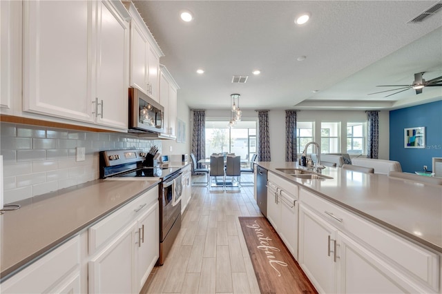 kitchen with a sink, visible vents, white cabinets, appliances with stainless steel finishes, and tasteful backsplash