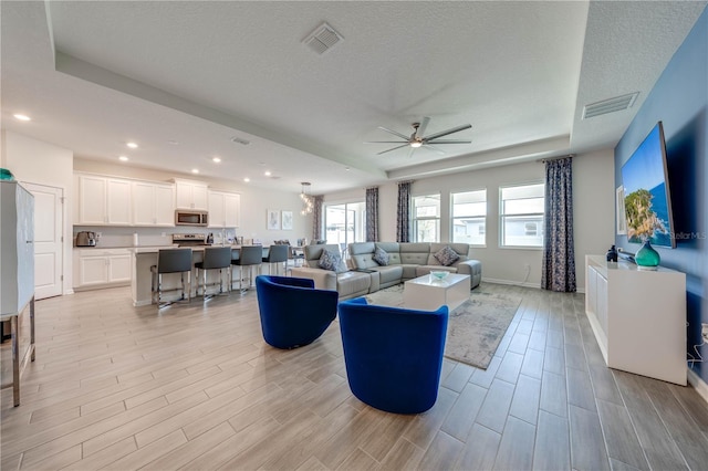 living room featuring wood tiled floor, visible vents, and a raised ceiling