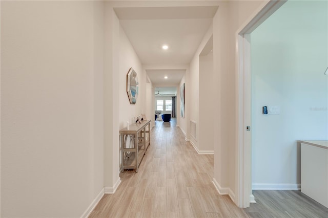 hallway with light wood-style floors, recessed lighting, visible vents, and baseboards