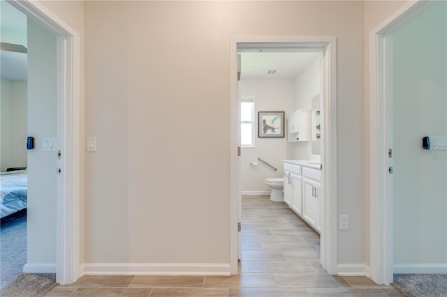 ensuite bathroom with baseboards, toilet, ensuite bathroom, wood tiled floor, and vanity