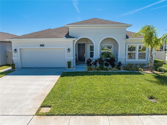 view of front of home featuring an attached garage, driveway, a front yard, and stucco siding