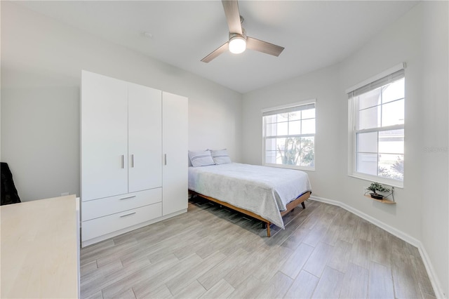 bedroom with a ceiling fan, light wood-style flooring, and baseboards