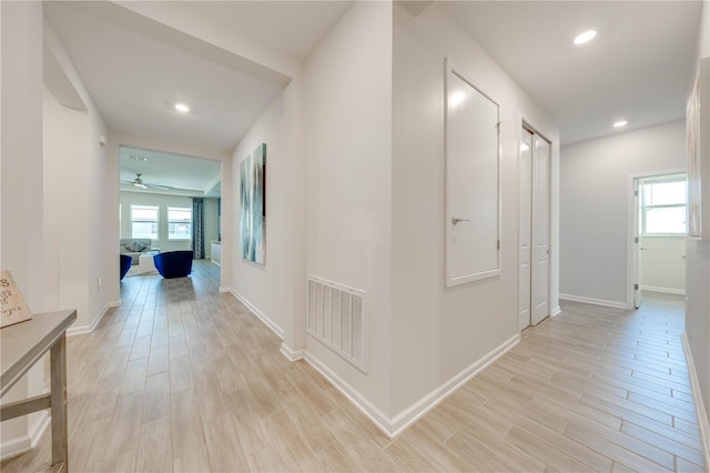 corridor featuring a healthy amount of sunlight, visible vents, and light wood finished floors