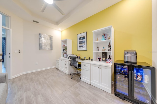 office featuring beverage cooler, visible vents, baseboards, a ceiling fan, and light wood-type flooring