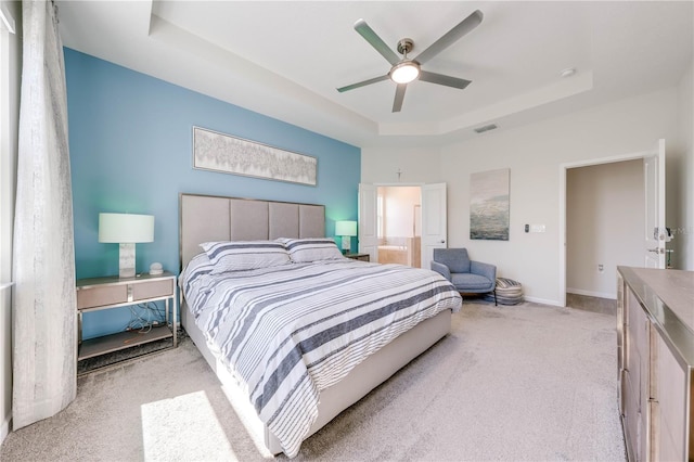 carpeted bedroom featuring baseboards, visible vents, a raised ceiling, and a ceiling fan