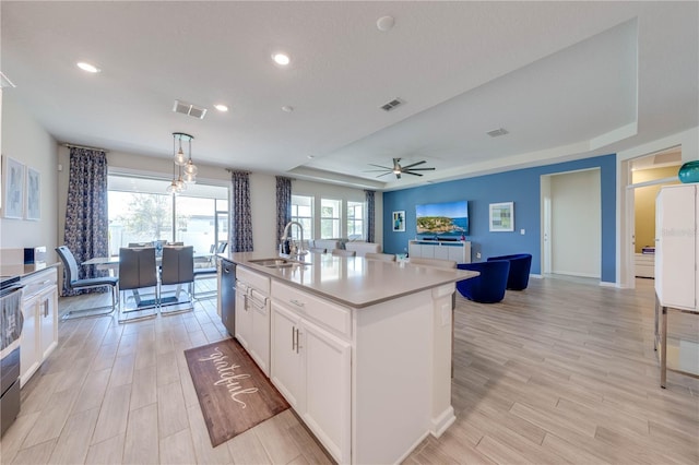 kitchen featuring a raised ceiling, visible vents, open floor plan, a sink, and dishwasher