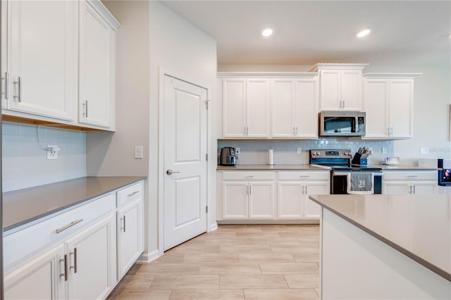 kitchen featuring tasteful backsplash, wood tiled floor, white cabinetry, and stainless steel appliances