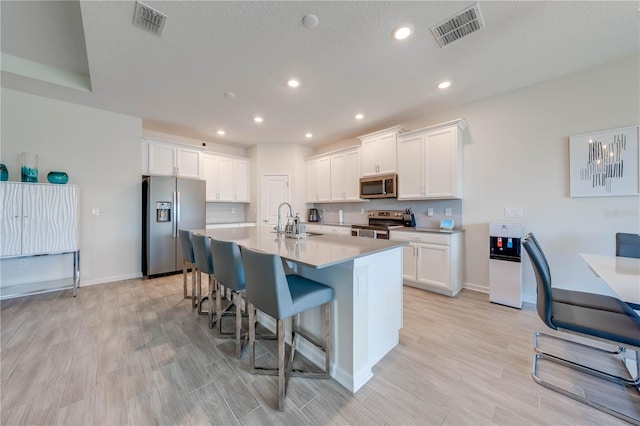 kitchen with stainless steel appliances, a sink, visible vents, and white cabinets