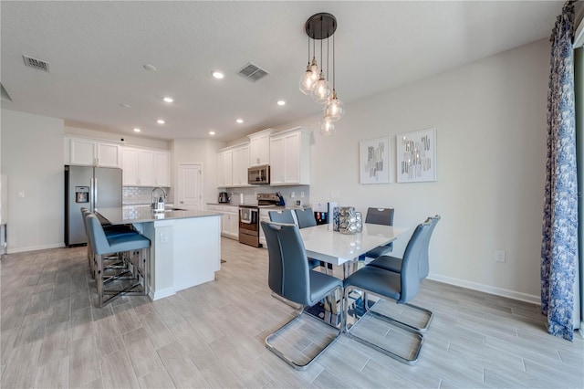 kitchen with appliances with stainless steel finishes, a kitchen island with sink, visible vents, and a sink