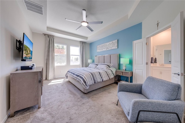 bedroom with a tray ceiling, visible vents, carpet flooring, ceiling fan, and baseboards