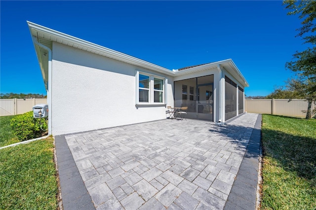 rear view of property featuring a sunroom, a fenced backyard, a patio, and stucco siding