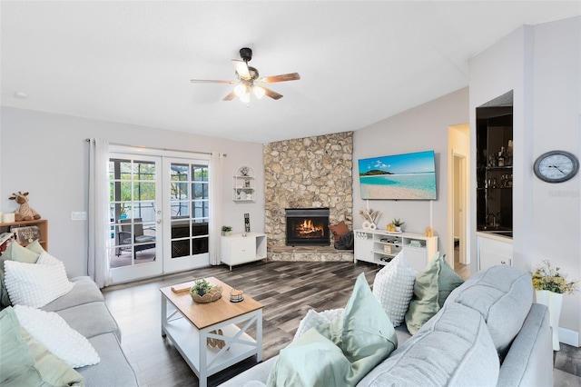 living area with ceiling fan, french doors, wood finished floors, and a stone fireplace