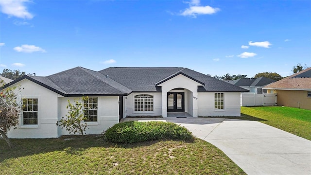 view of front of home with a shingled roof, fence, french doors, a front lawn, and stucco siding