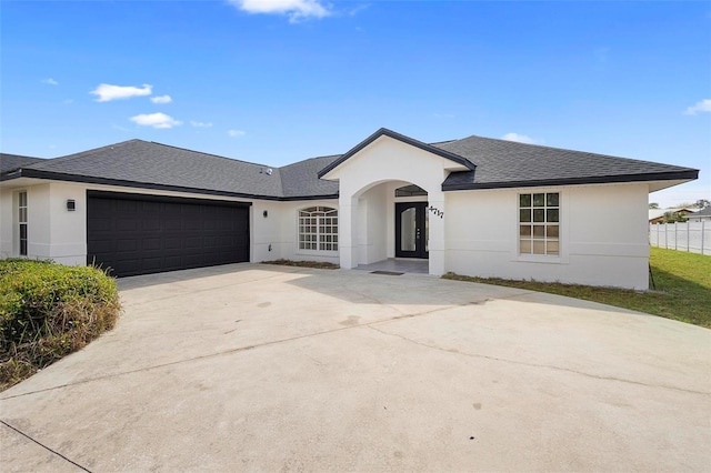 ranch-style home with roof with shingles, stucco siding, fence, a garage, and driveway