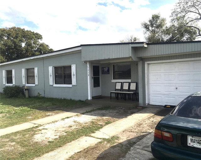 view of front facade featuring a porch, an attached garage, and concrete block siding