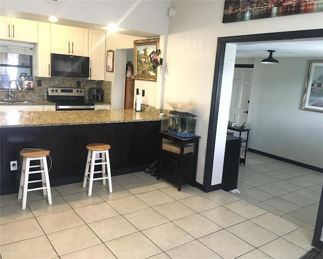 kitchen with electric range, decorative backsplash, black microwave, a sink, and light tile patterned flooring