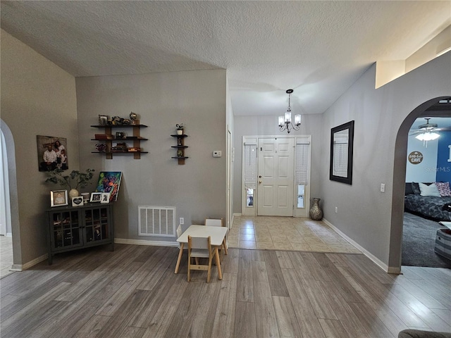 foyer entrance with arched walkways, wood finished floors, and visible vents