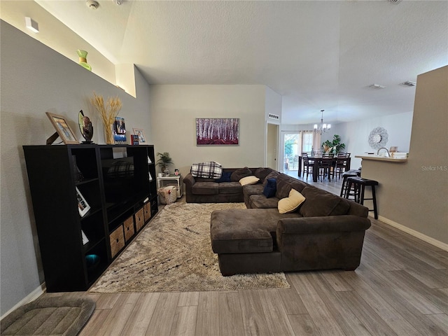 living area with a chandelier, wood finished floors, visible vents, and baseboards