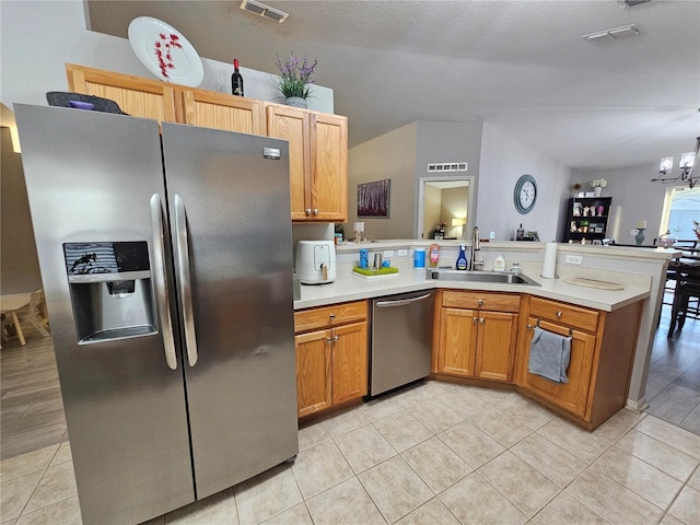 kitchen featuring visible vents, a peninsula, an inviting chandelier, stainless steel appliances, and a sink