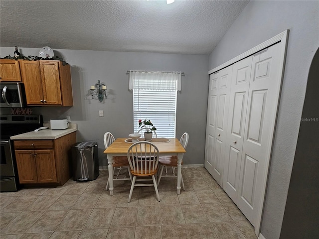 dining space with baseboards, a textured ceiling, and light tile patterned flooring