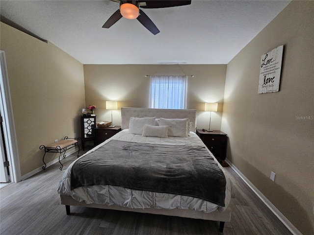 bedroom with ceiling fan, baseboards, and wood finished floors