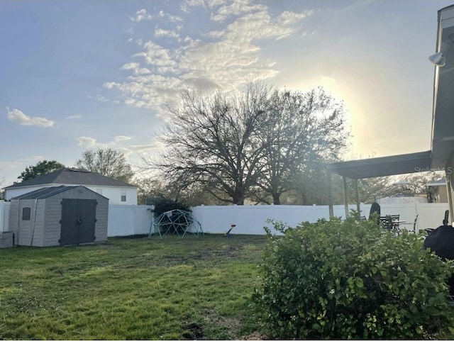 view of yard featuring a fenced backyard, a storage unit, and an outdoor structure